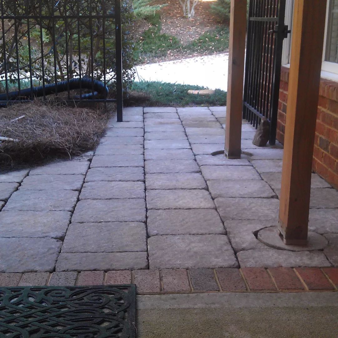 A brick walkway with a fence in the background