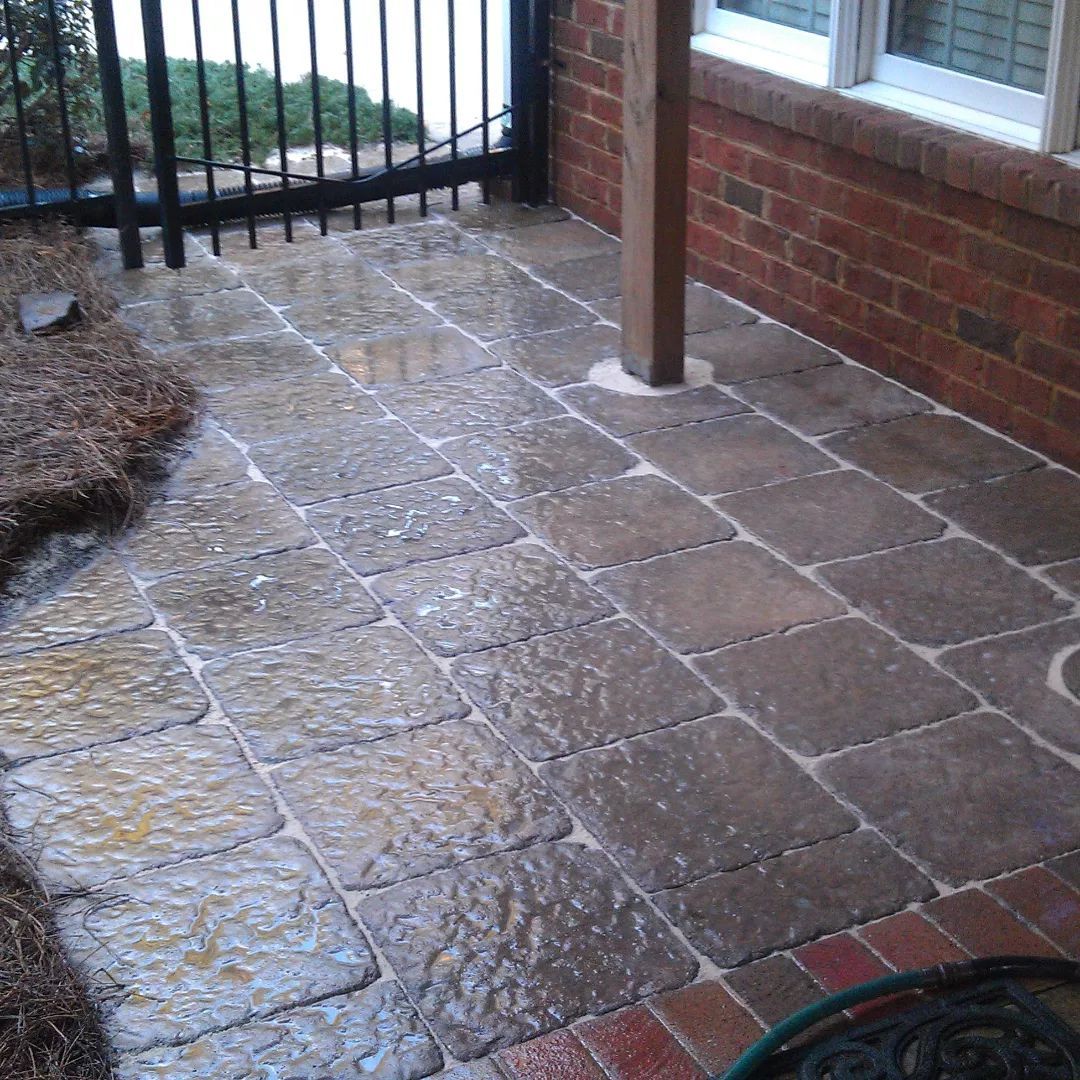 A brick walkway leading to a brick building with a fence and a window.