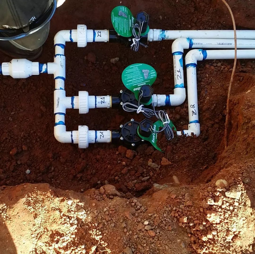 A bunch of pipes and valves are laying in the dirt