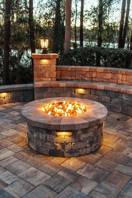 A fire pit is sitting on a patio next to a brick wall.