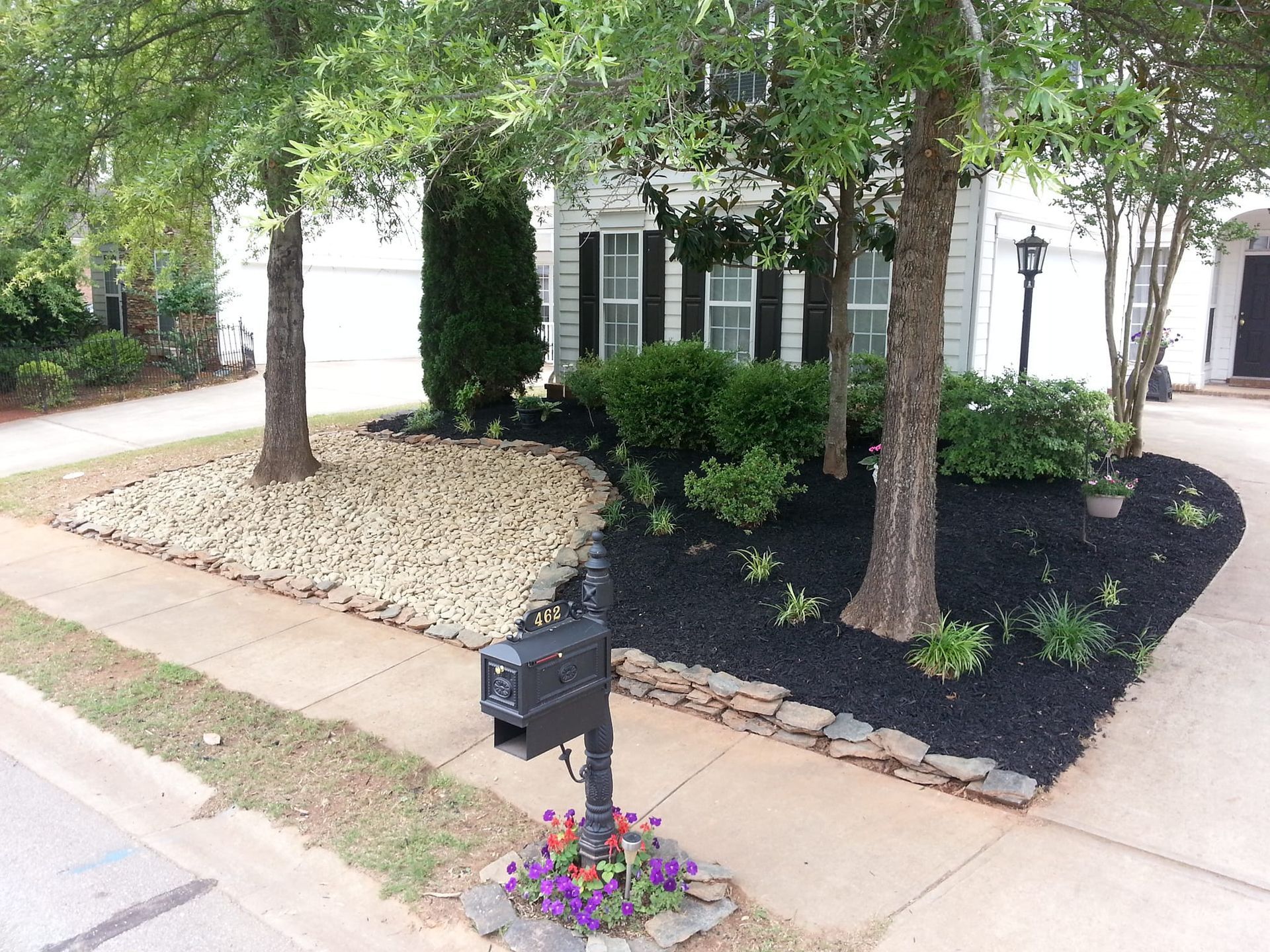 A mailbox is in front of a house with a lush green yard. valley falls 