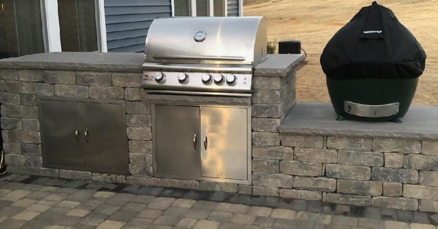 A stainless steel grill is sitting on top of a stone wall.
