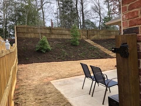 A backyard with a wooden fence and chairs in front of a brick house. valley falls 