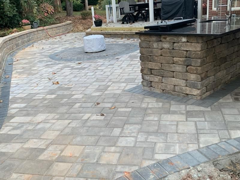 A brick patio with a grill and a table in the middle of it.