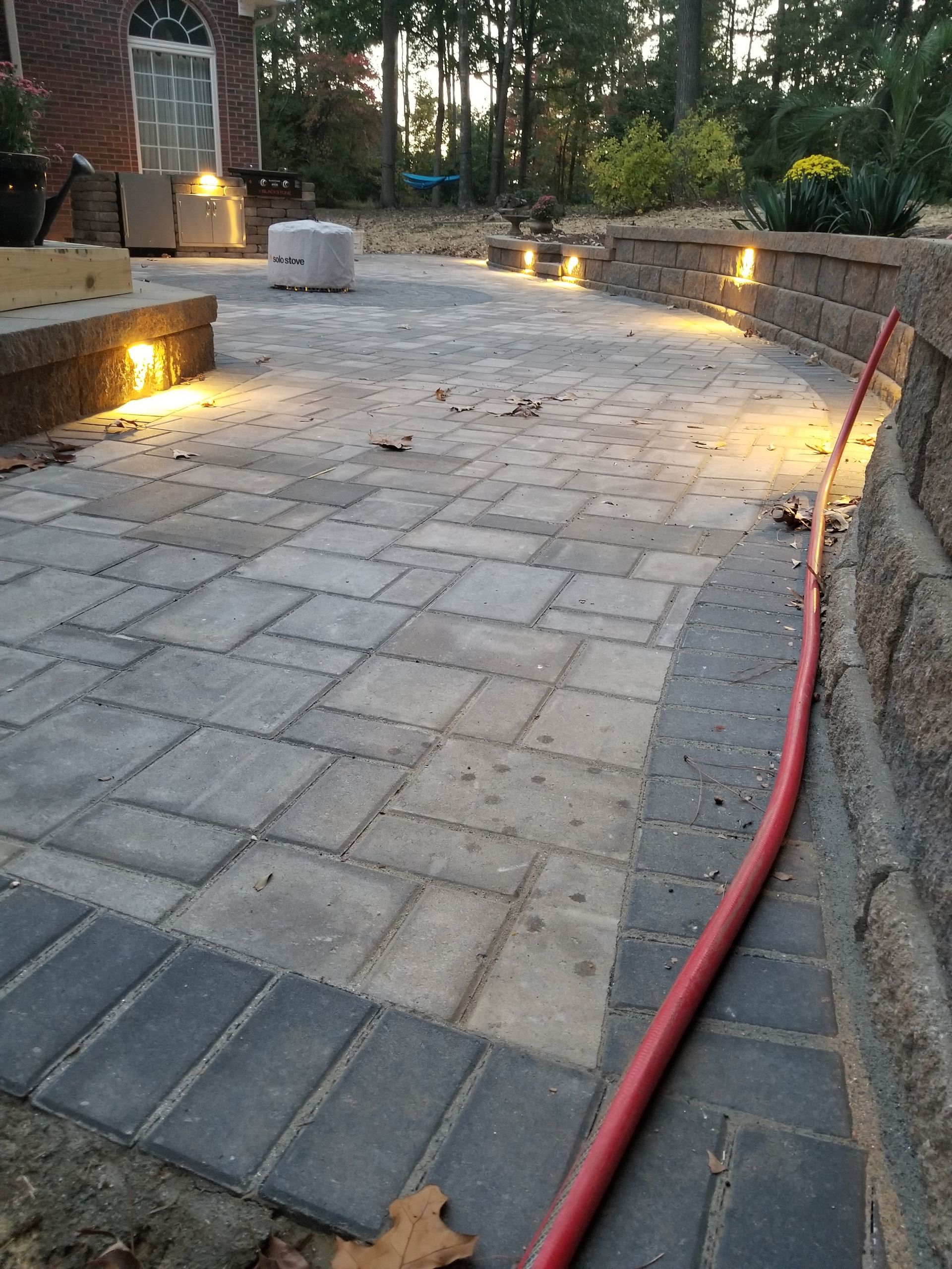 A red hose is connected to a brick walkway