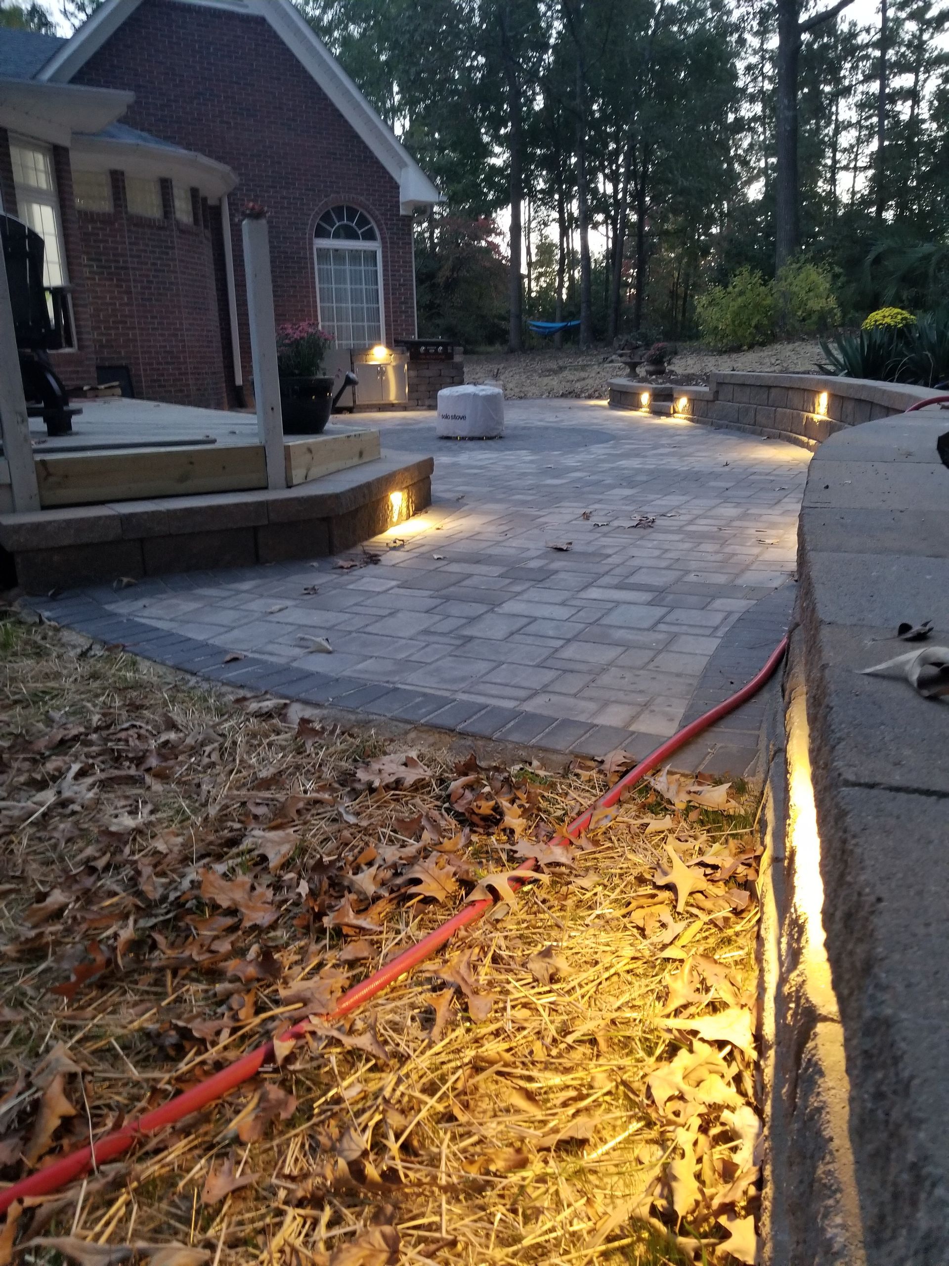 A brick house is behind a patio with lights on it