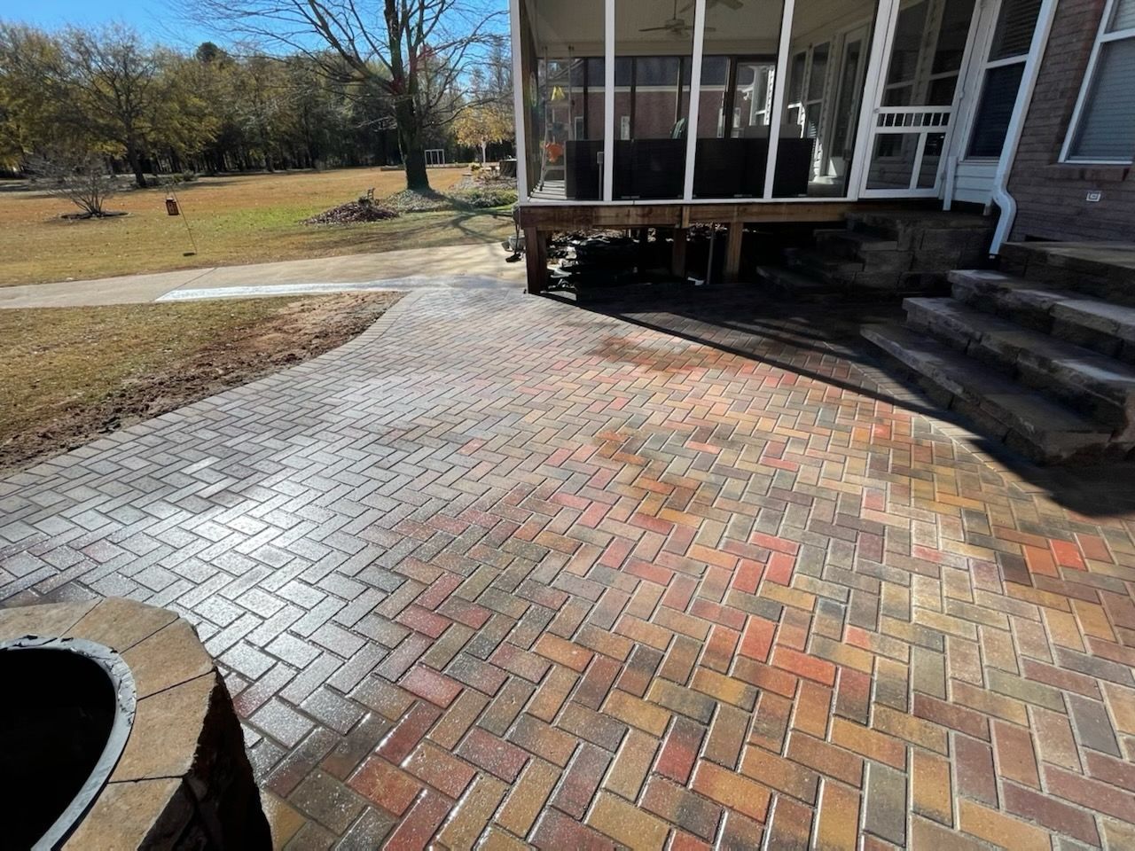 A brick patio with a screened in porch next to a house.