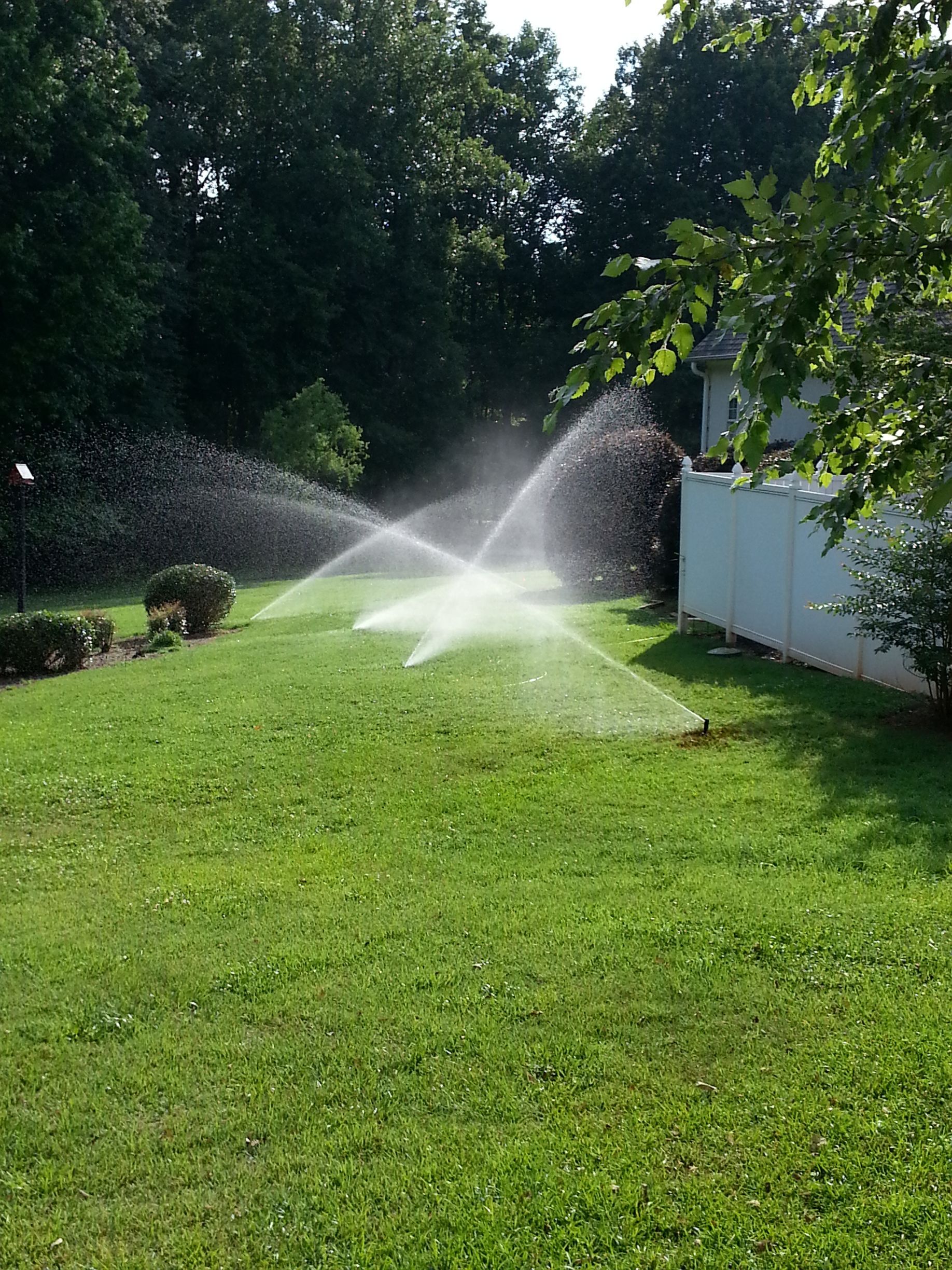 A lawn with sprinklers spraying water on it