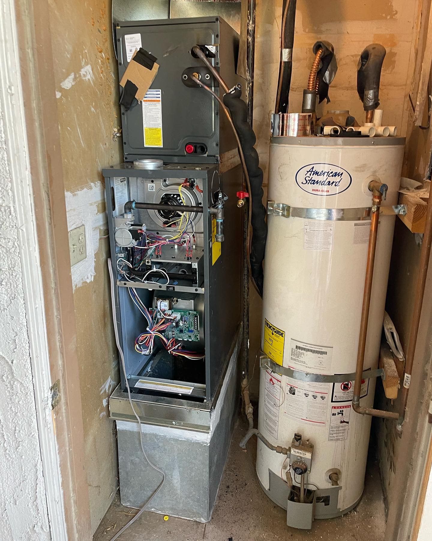 A water heater is sitting next to an air conditioner in a room.