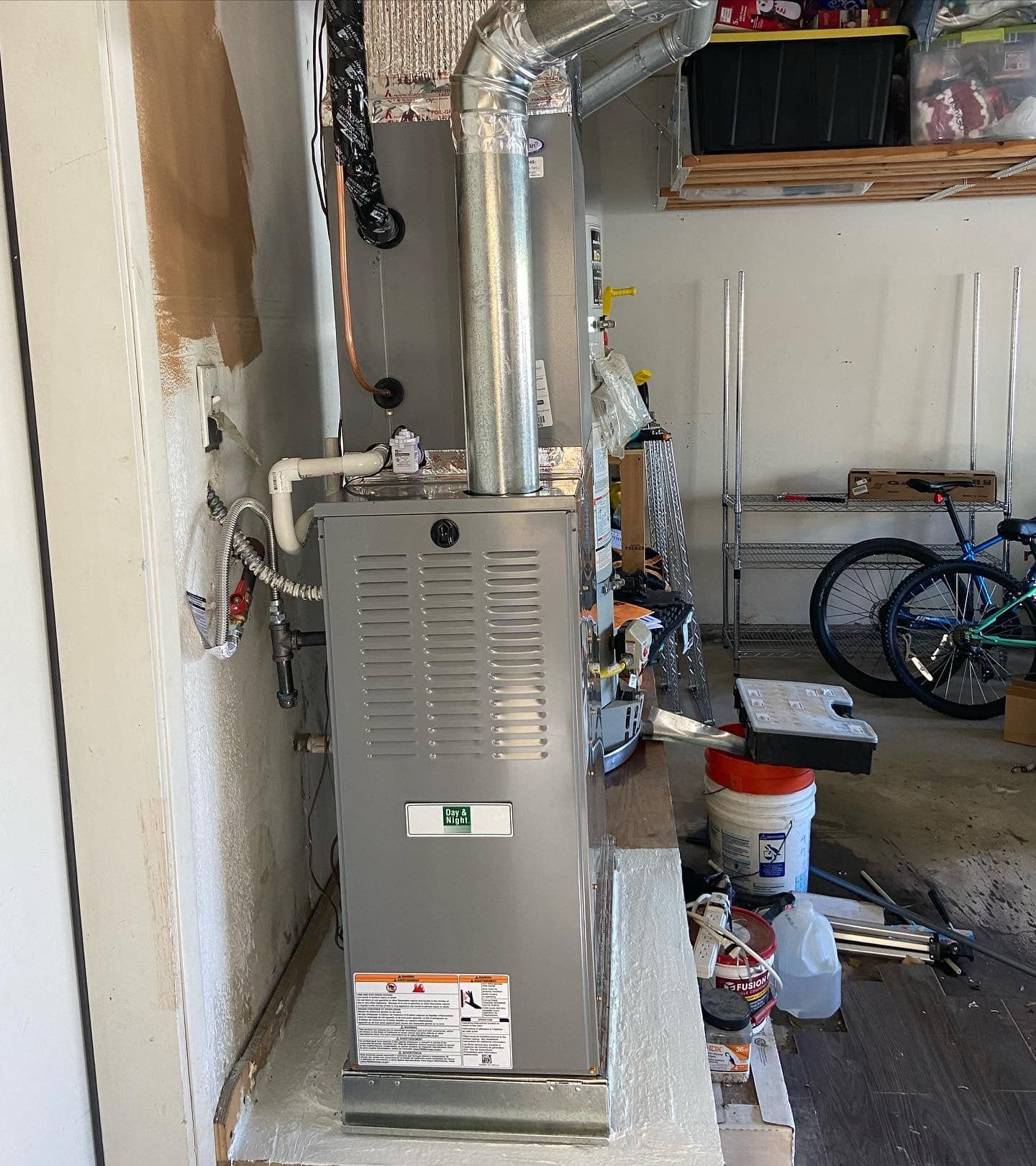 A gas heater is sitting in a garage next to a bicycle.