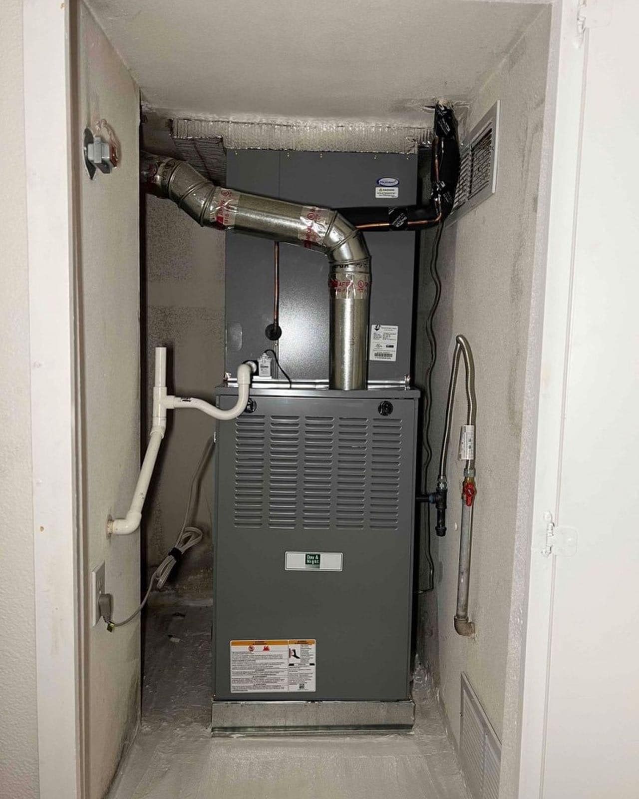 An air conditioner is sitting in a corner of a room next to a door.