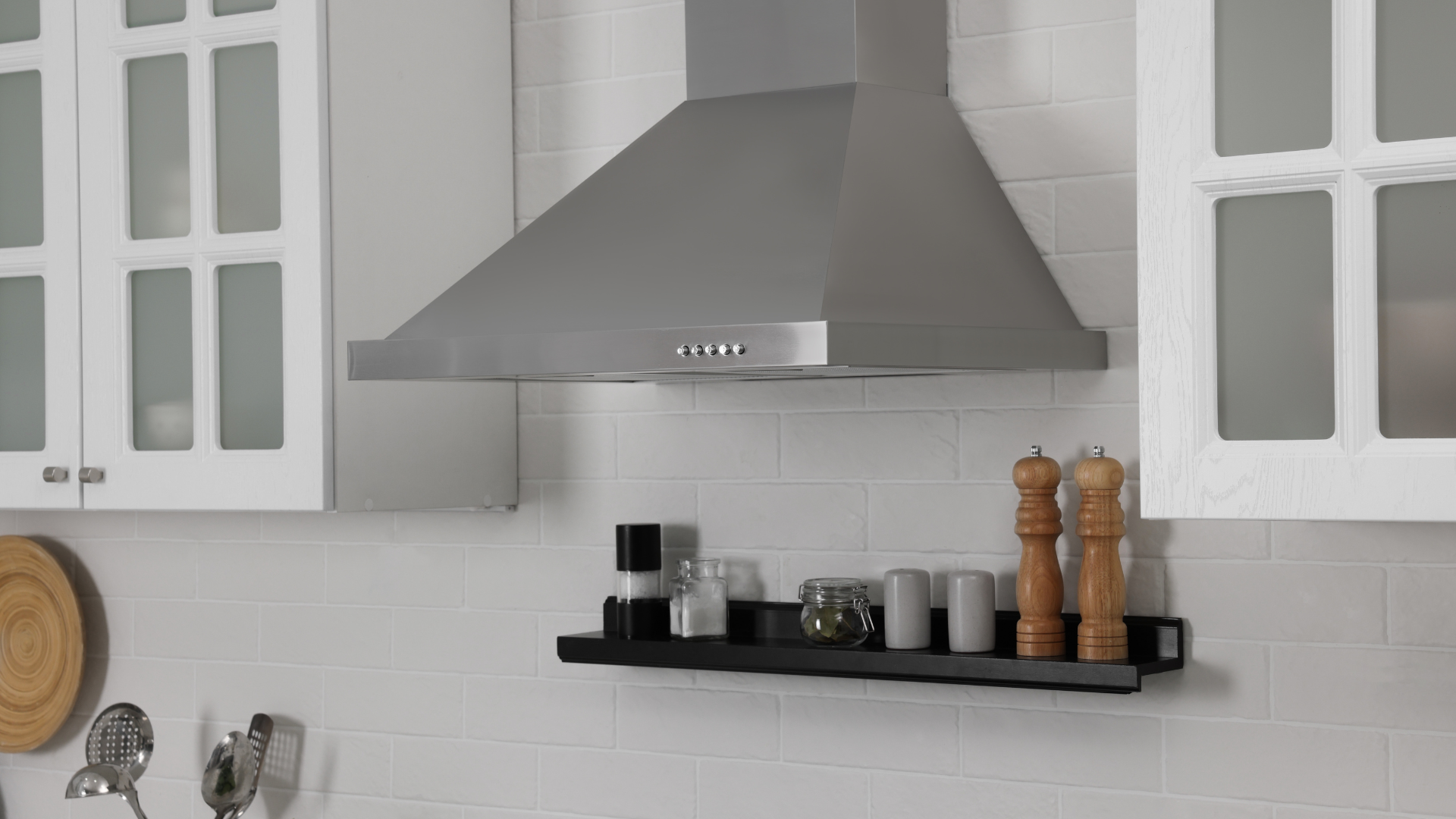 A kitchen with a stainless steel hood and a black shelf.