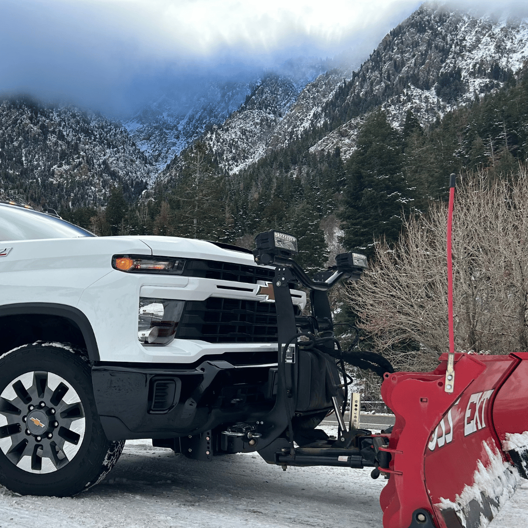 Activescapes Landscaping snow removal service truck with plow parked in Taylorsville, Utah near a snow-covered mountain landscape.