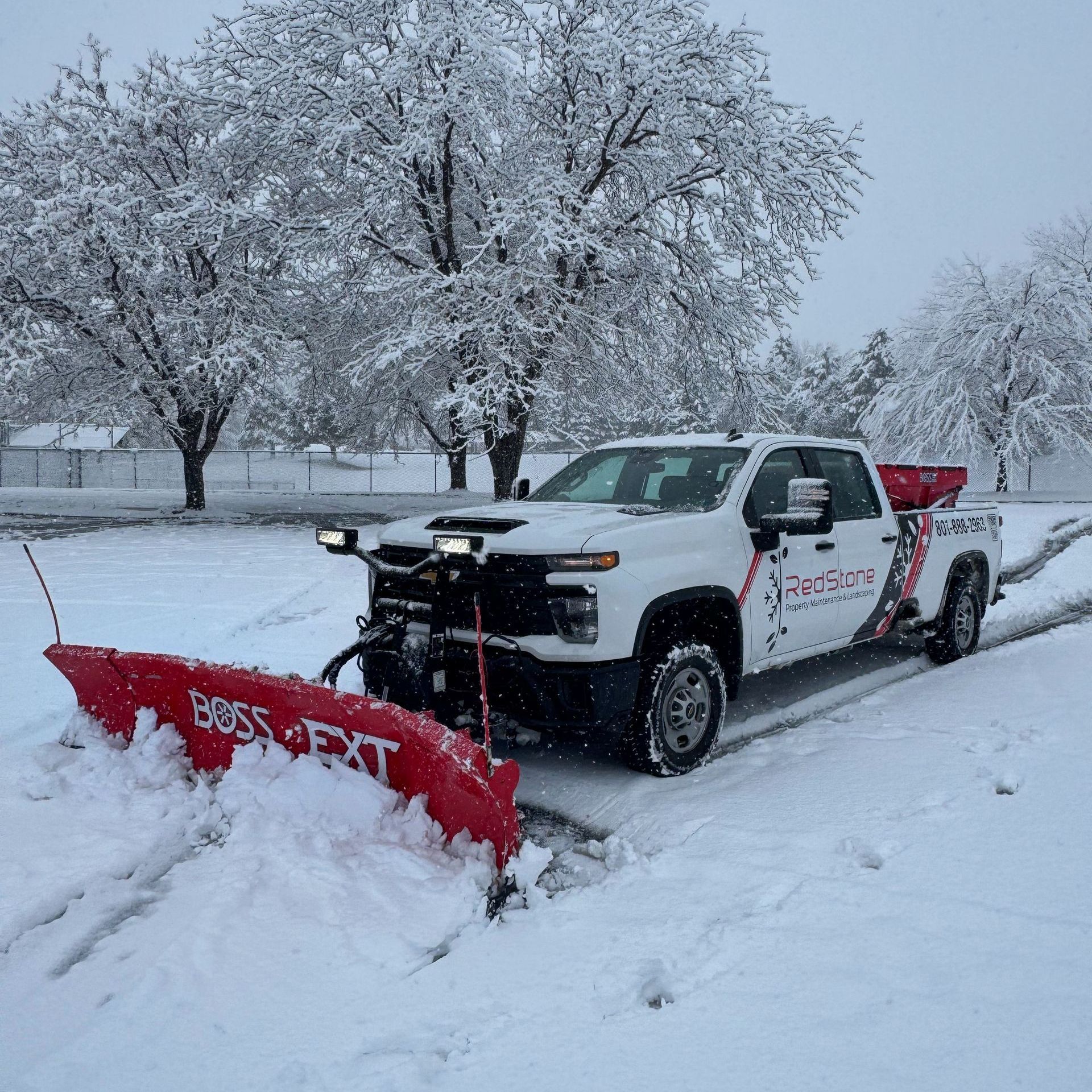A man is holding a shovel in front of a snow plow.