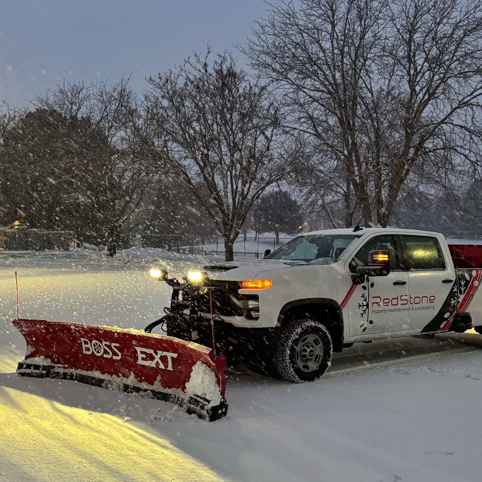 A man is holding a shovel in front of a snow plow.