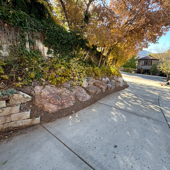 A stone wall along the side of a road next to a house.