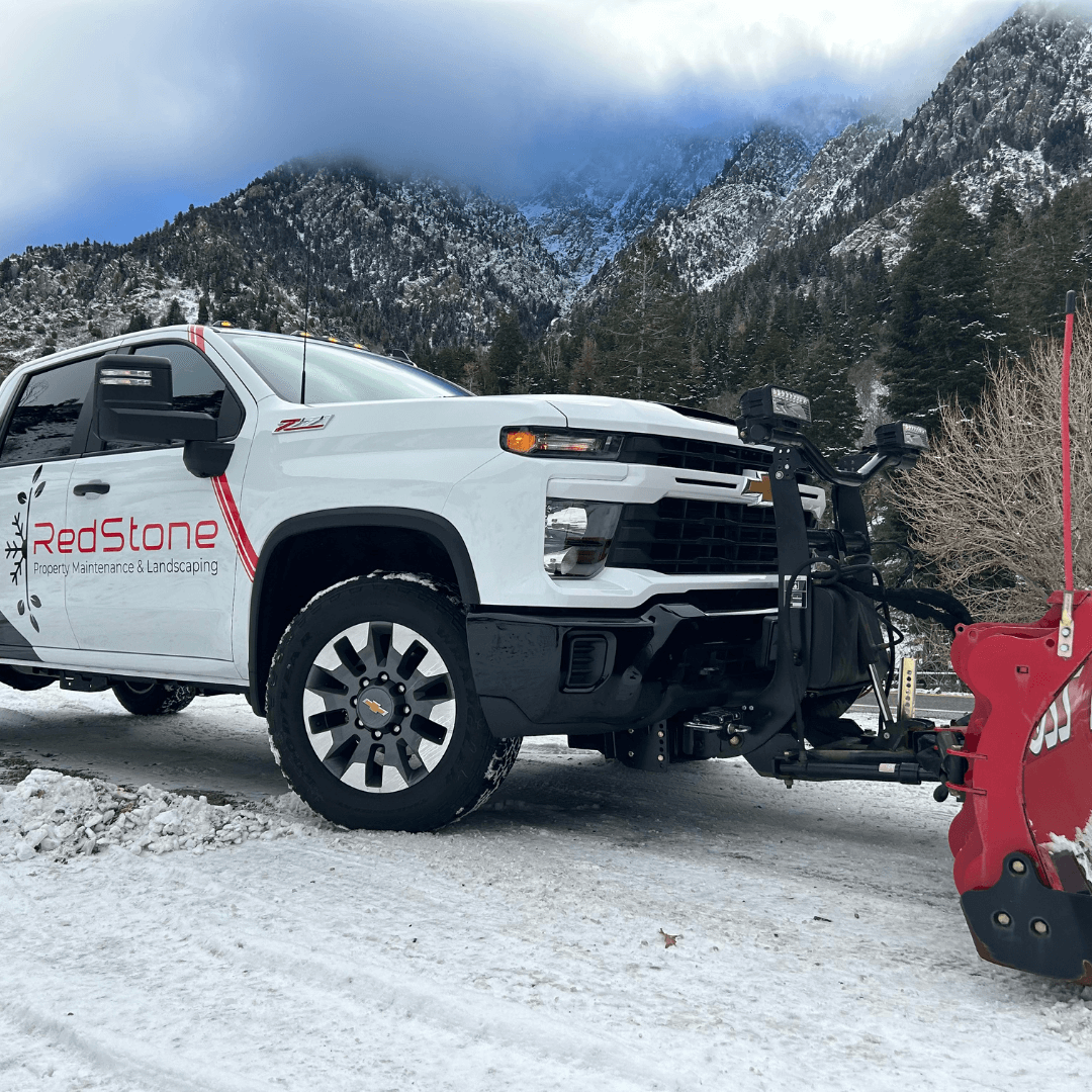 A man is holding a shovel in front of a snow plow.