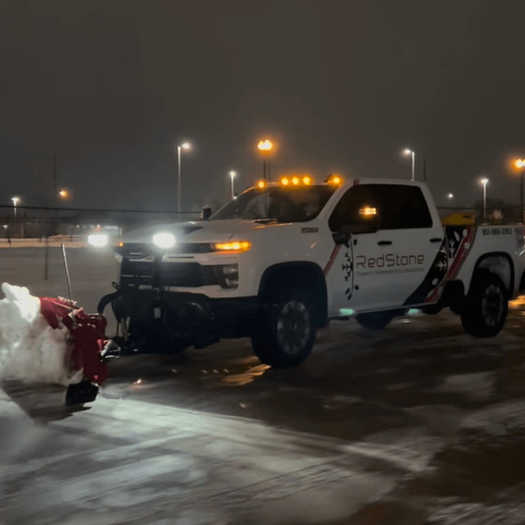 A man is holding a shovel in front of a snow plow.
