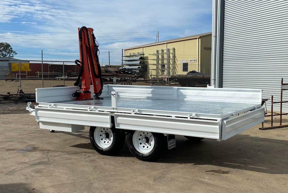 A Trailer With a Crane Attached to It is Parked in Front of a Building — SNS Custom Fabrication in Gin Gin, QLD