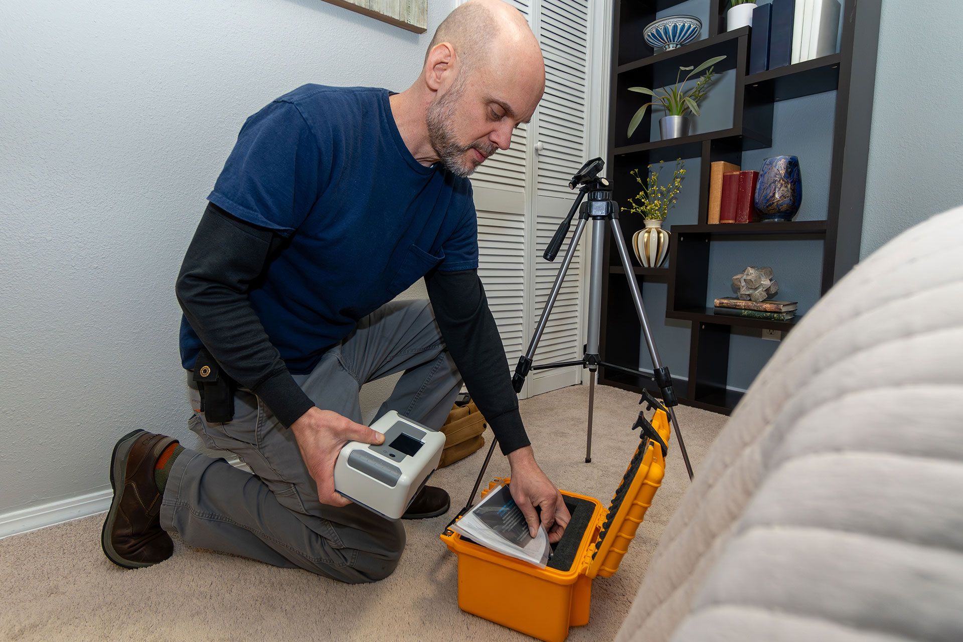 A man is kneeling on the floor using a device.