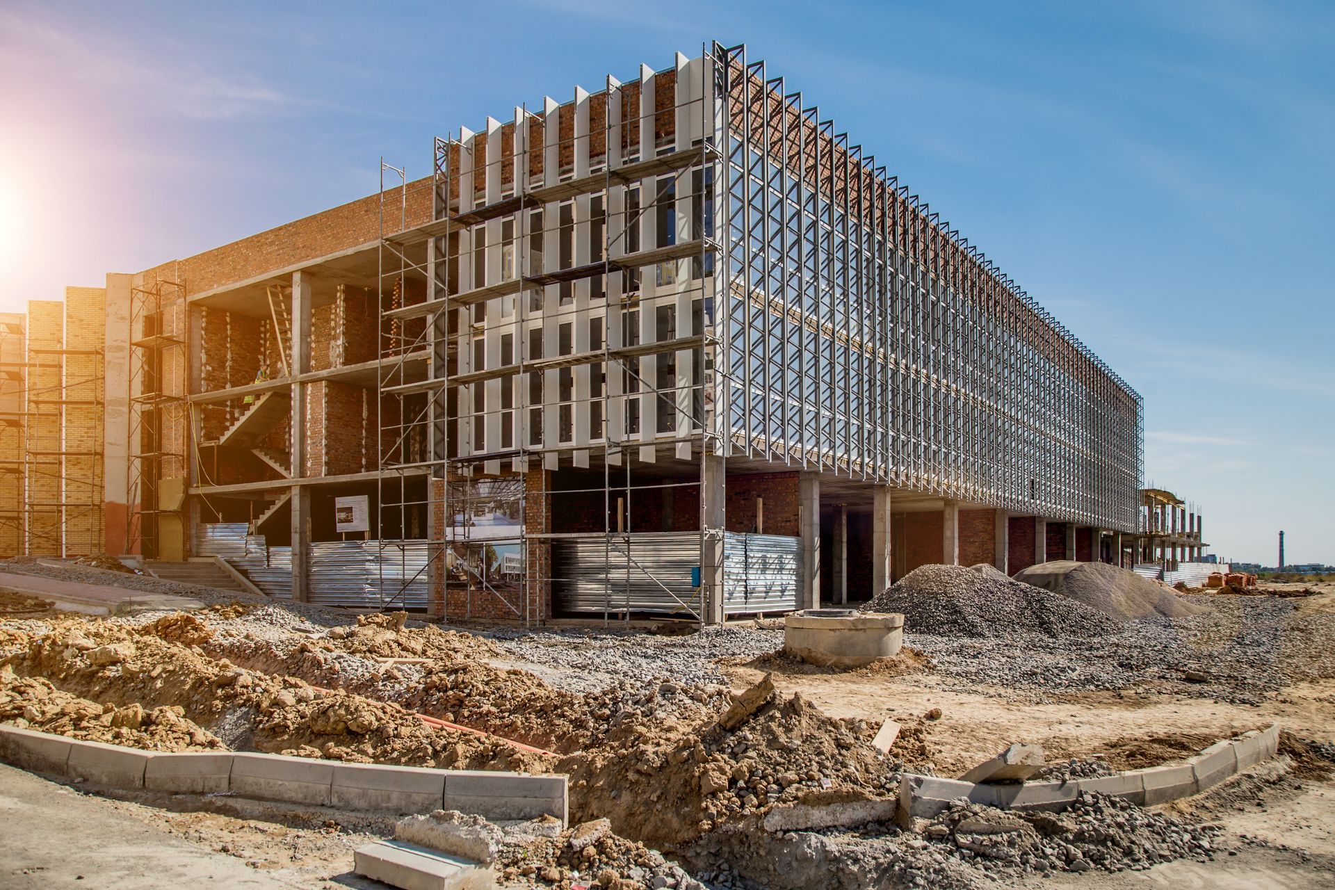 Un grand bâtiment est en construction au milieu d'un champ de terre.