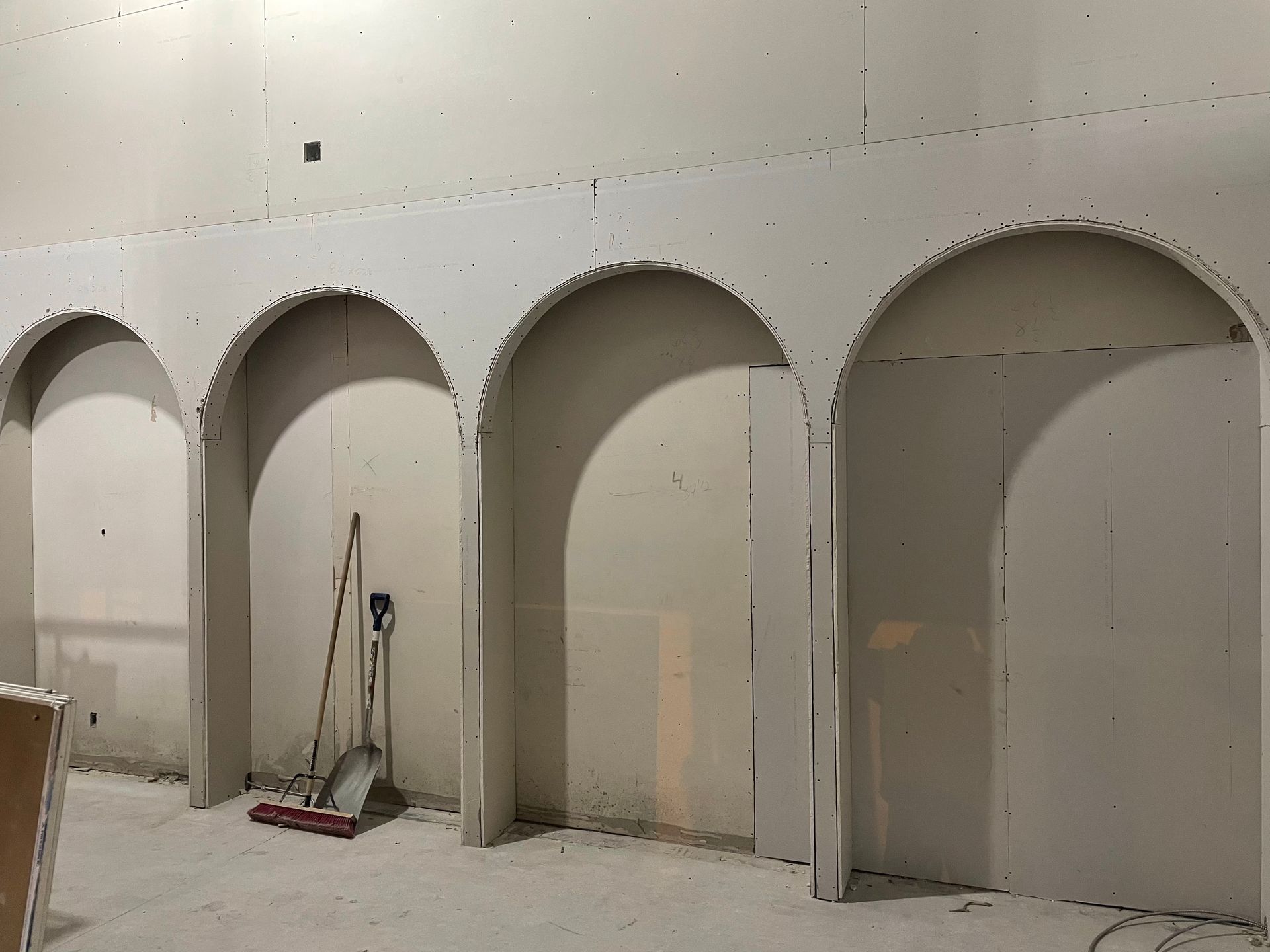 Une pièce avec des arches et un balai au sol.