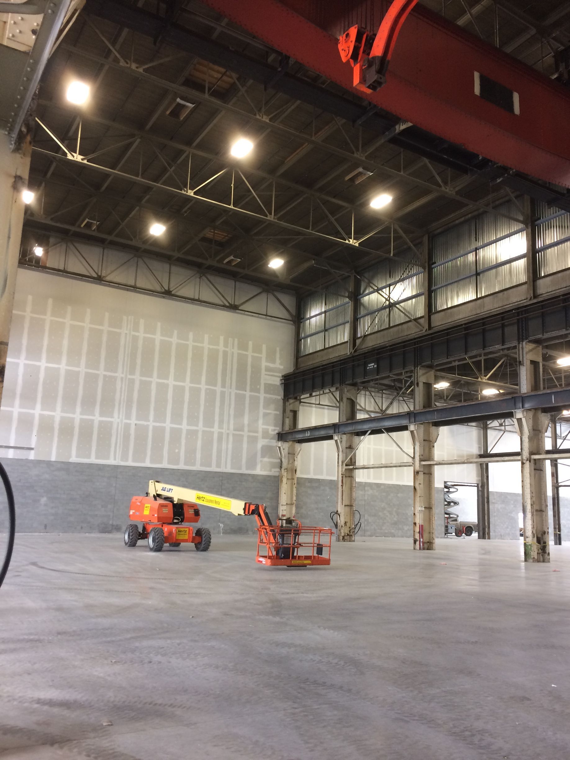 Un grand entrepôt vide avec une grue au milieu.