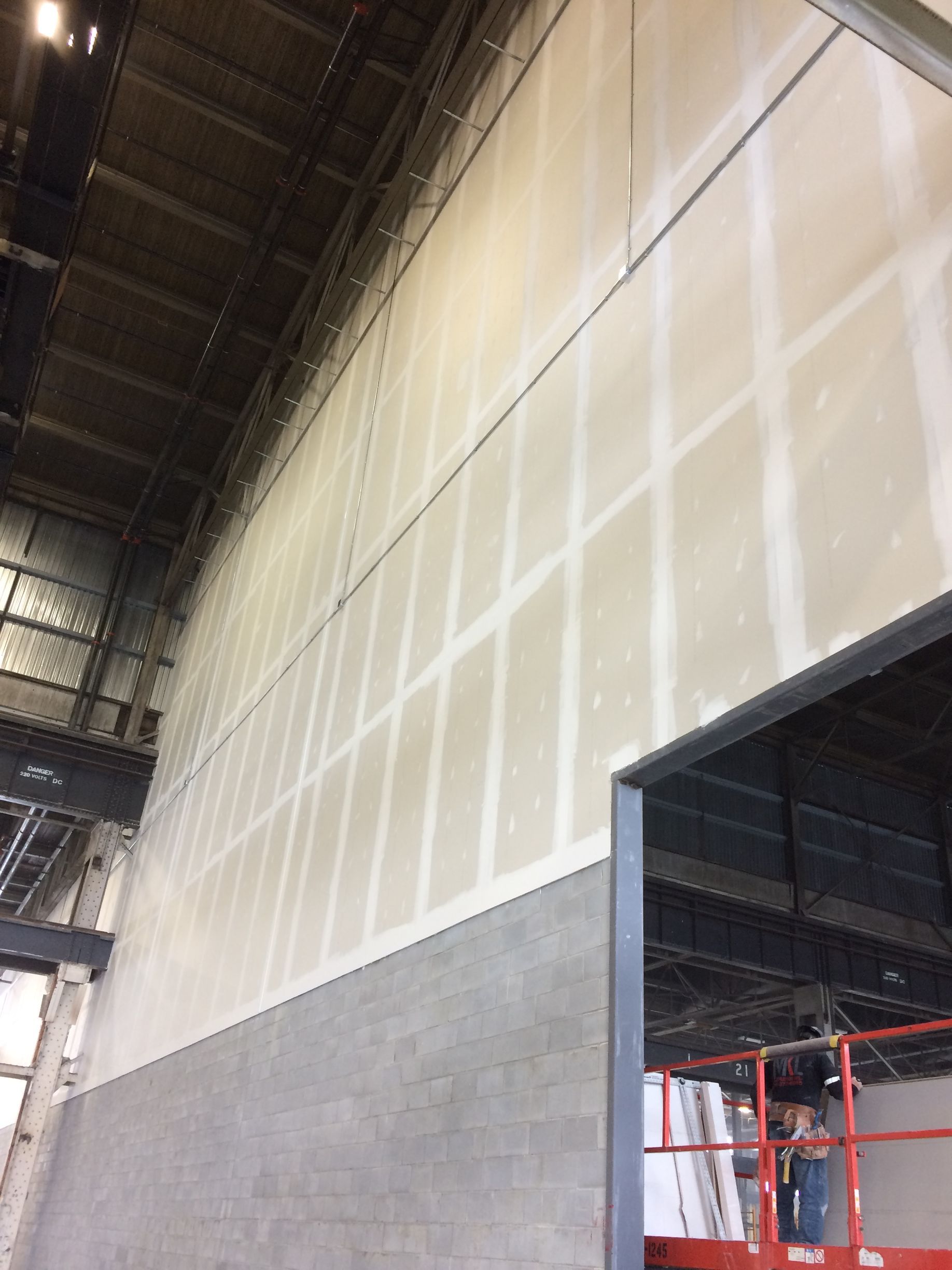 Un homme se tient debout sur un ascenseur devant un grand mur.