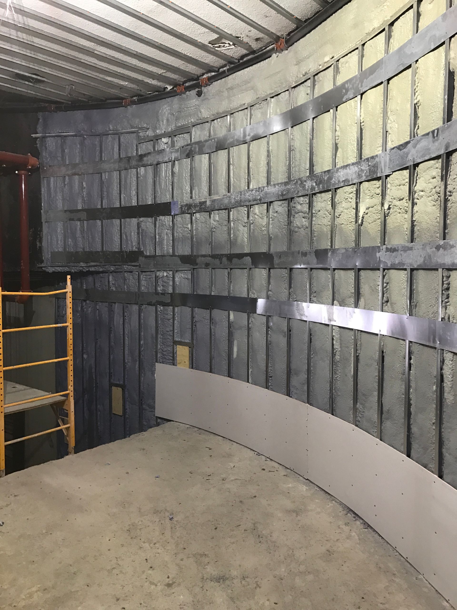 Une pièce avec un mur incurvé et un échafaudage en arrière-plan.