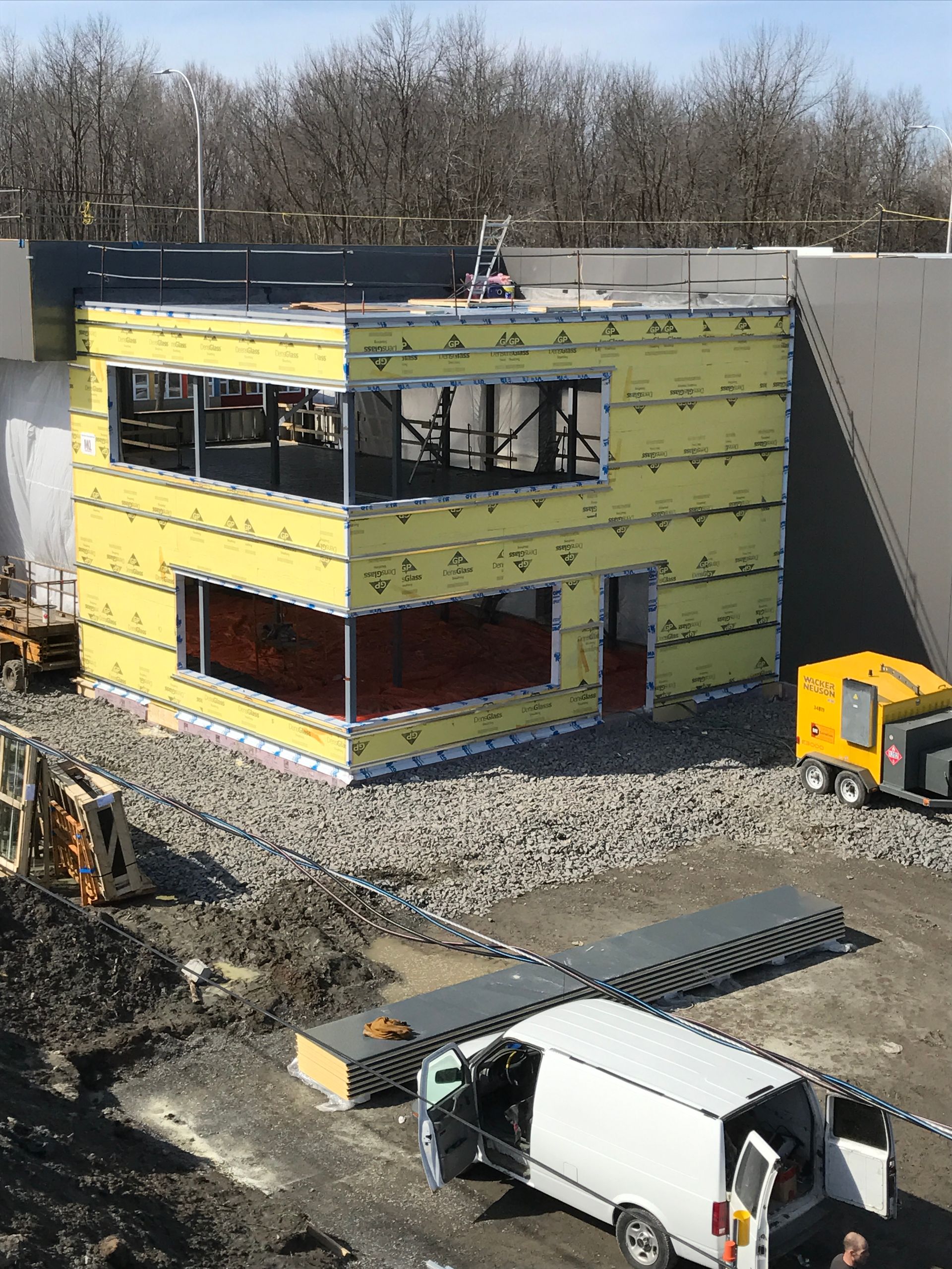 Une camionnette blanche est garée devant un immeuble en construction.