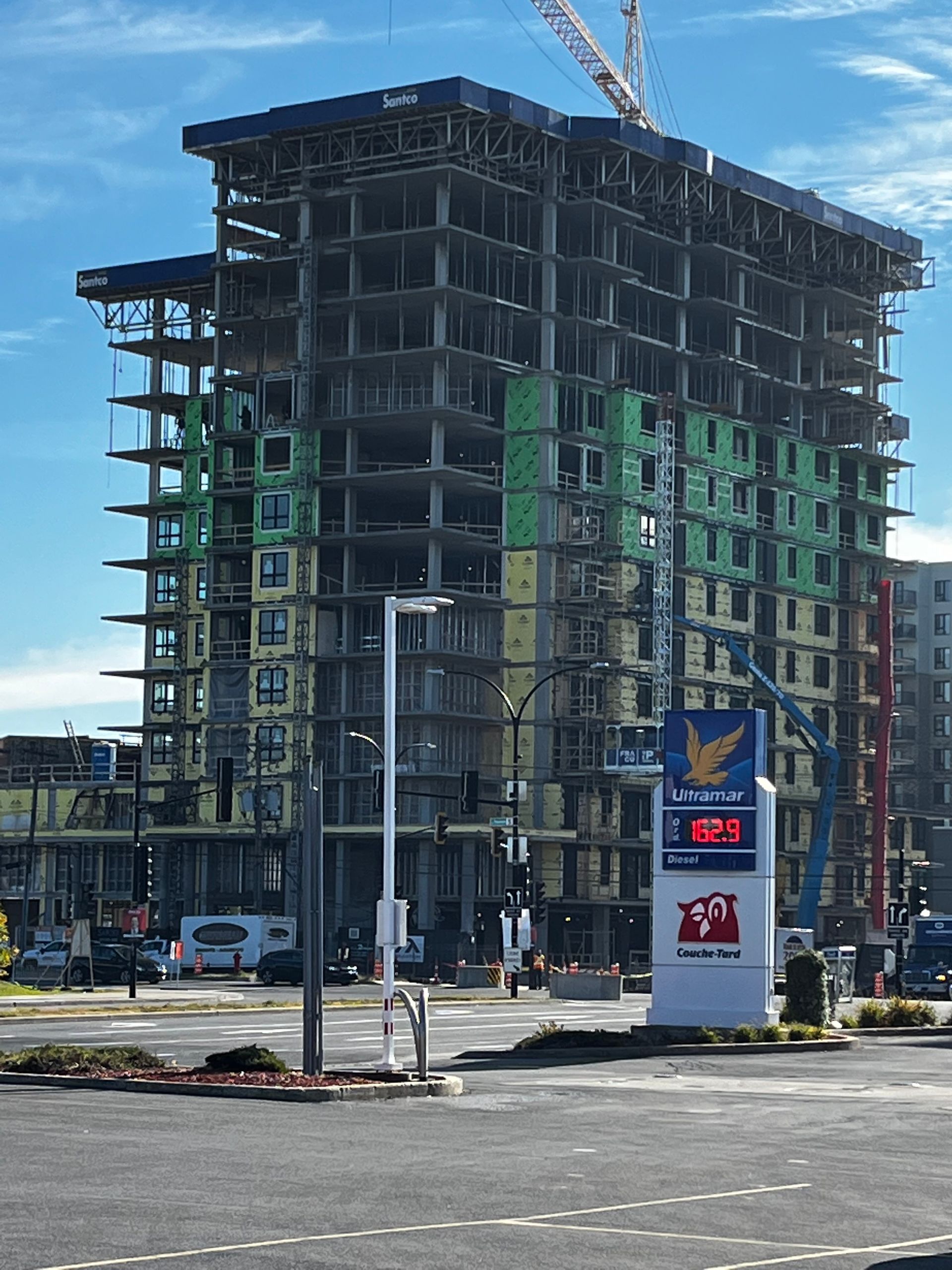 Un grand bâtiment est en construction à côté d'une station-service.