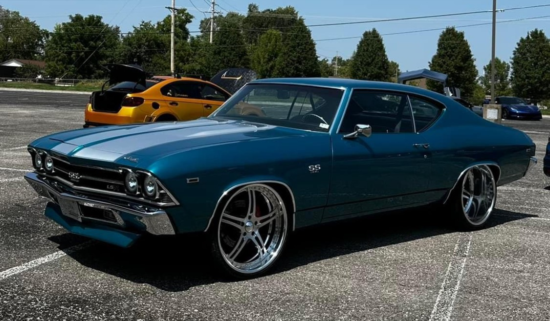 A blue car is parked in a parking lot next to a yellow car