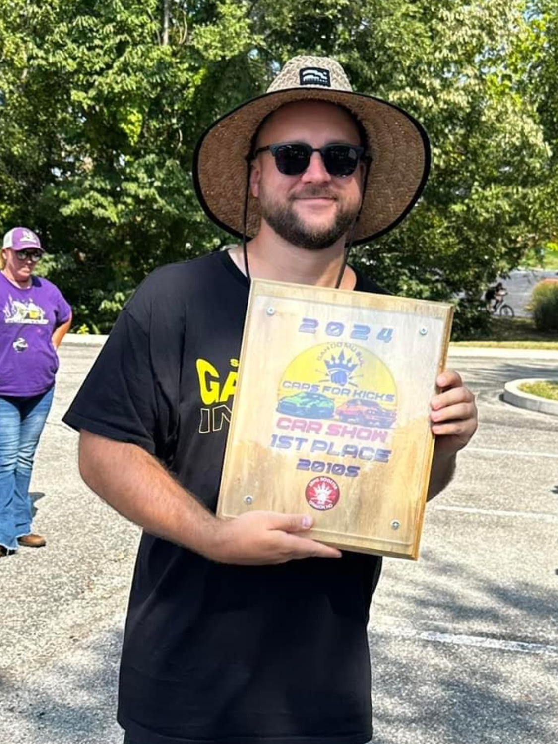 A man wearing a hat and sunglasses is holding a plaque.