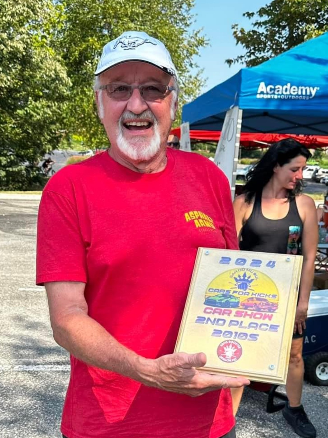 A man in a red shirt is holding a plaque.