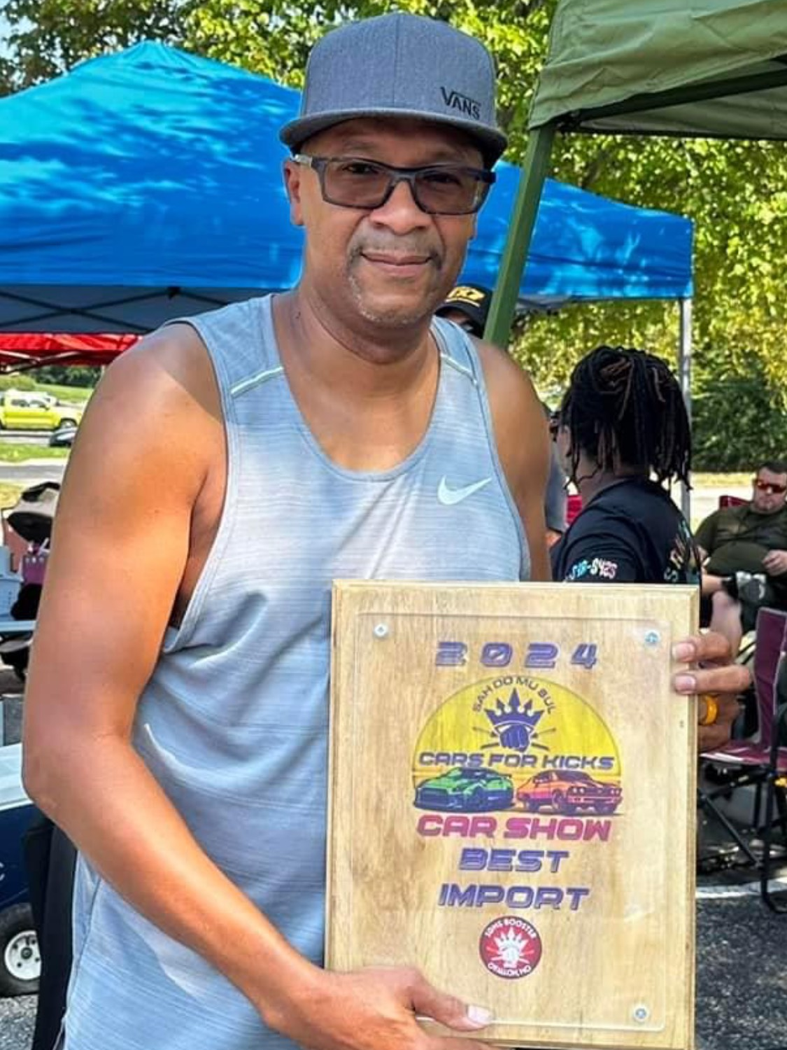 A man is holding a wooden plaque that says best import