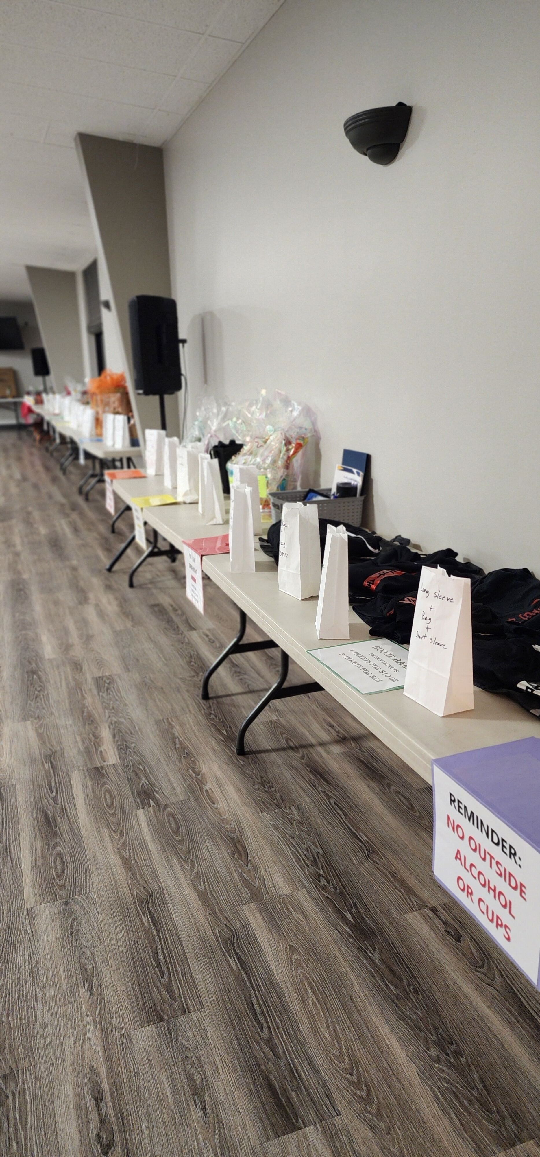 A long row of folding tables filled with various items in a room.
