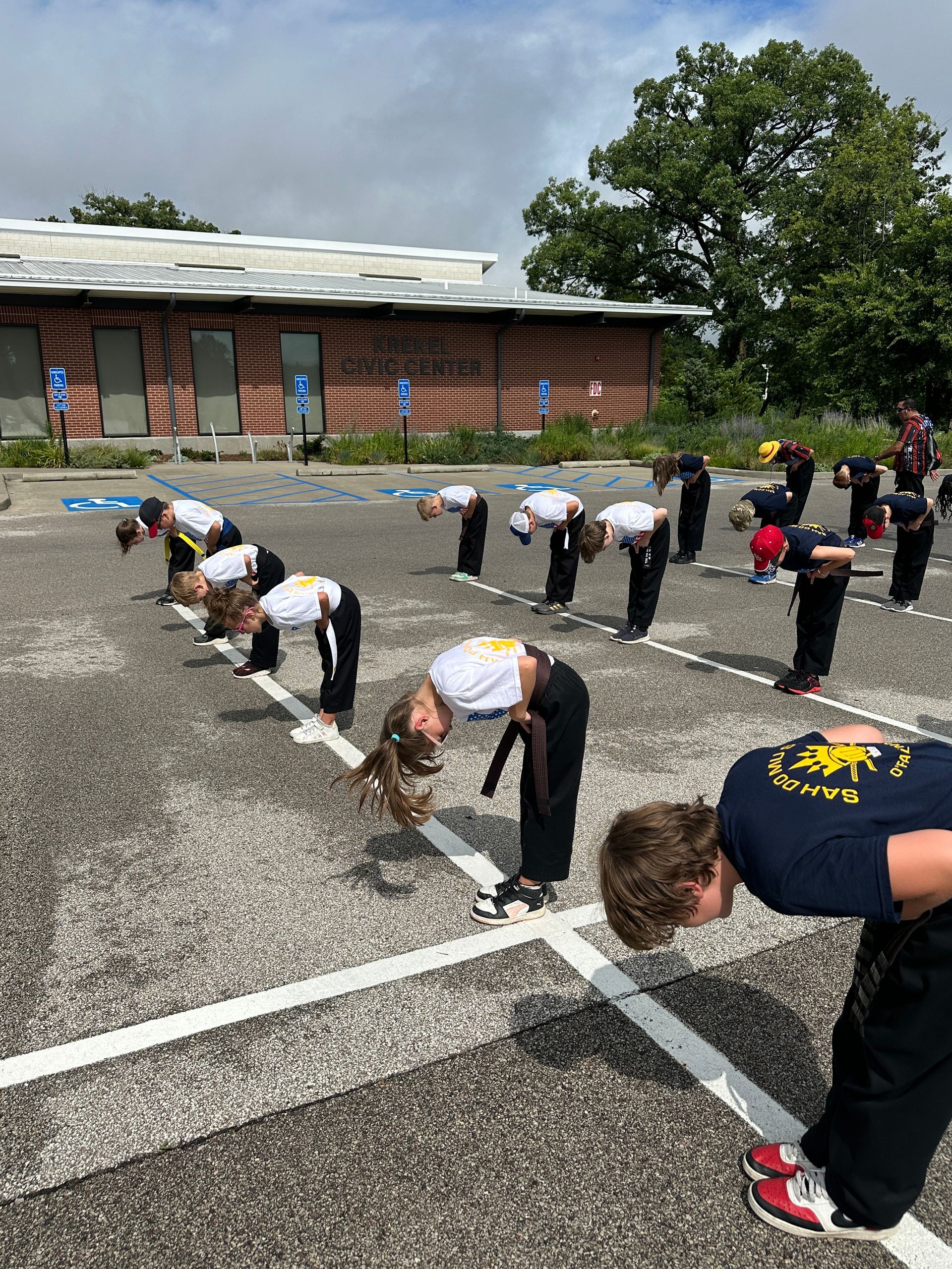 A group of people are doing stretching exercises in a parking lot.