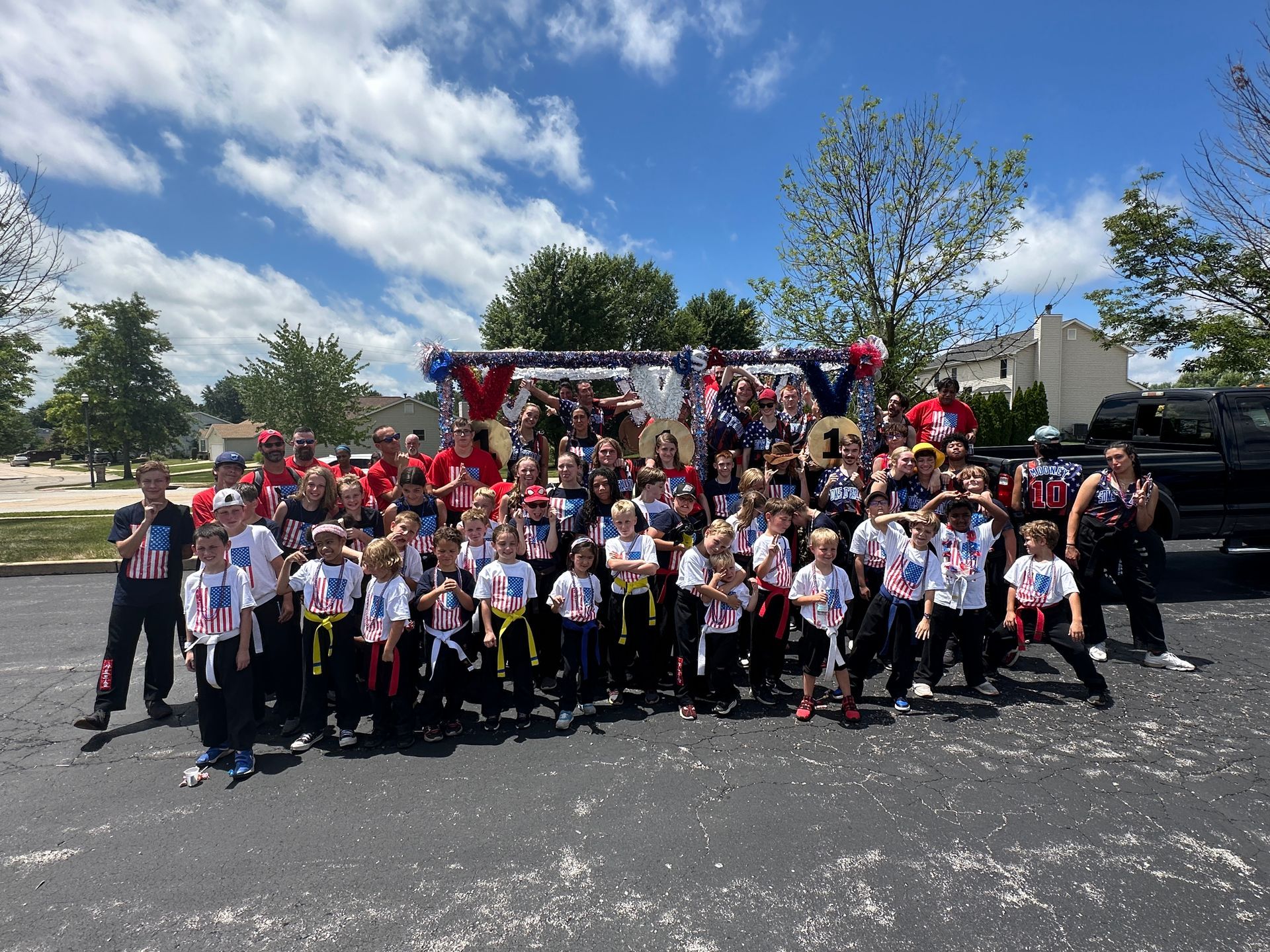 A large group of people are posing for a picture in a parking lot.
