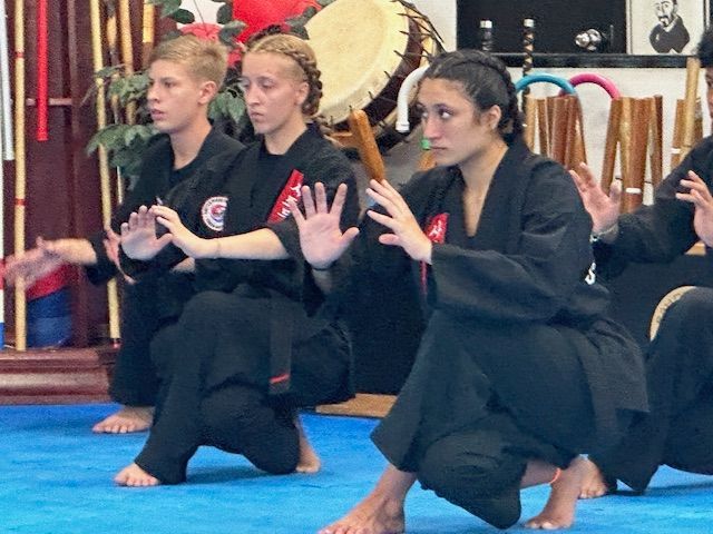 A group of people are practicing martial arts on a blue mat
