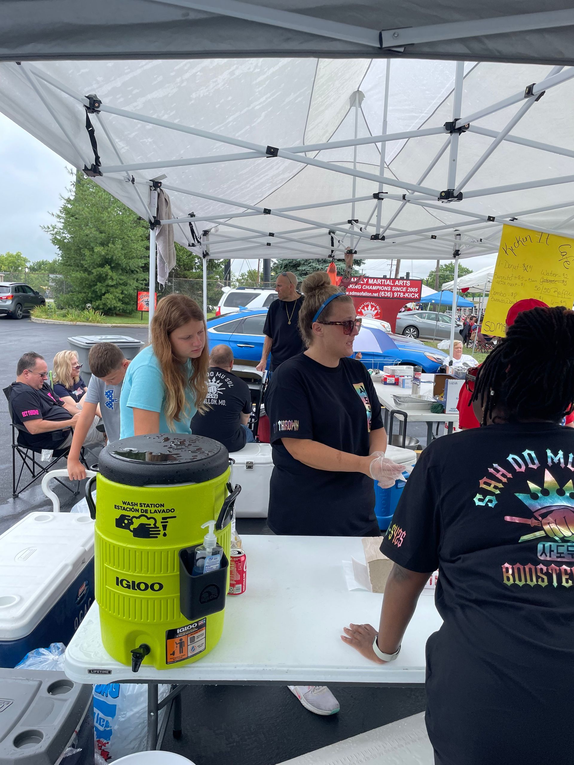 A group of people are standing around a table under a tent.