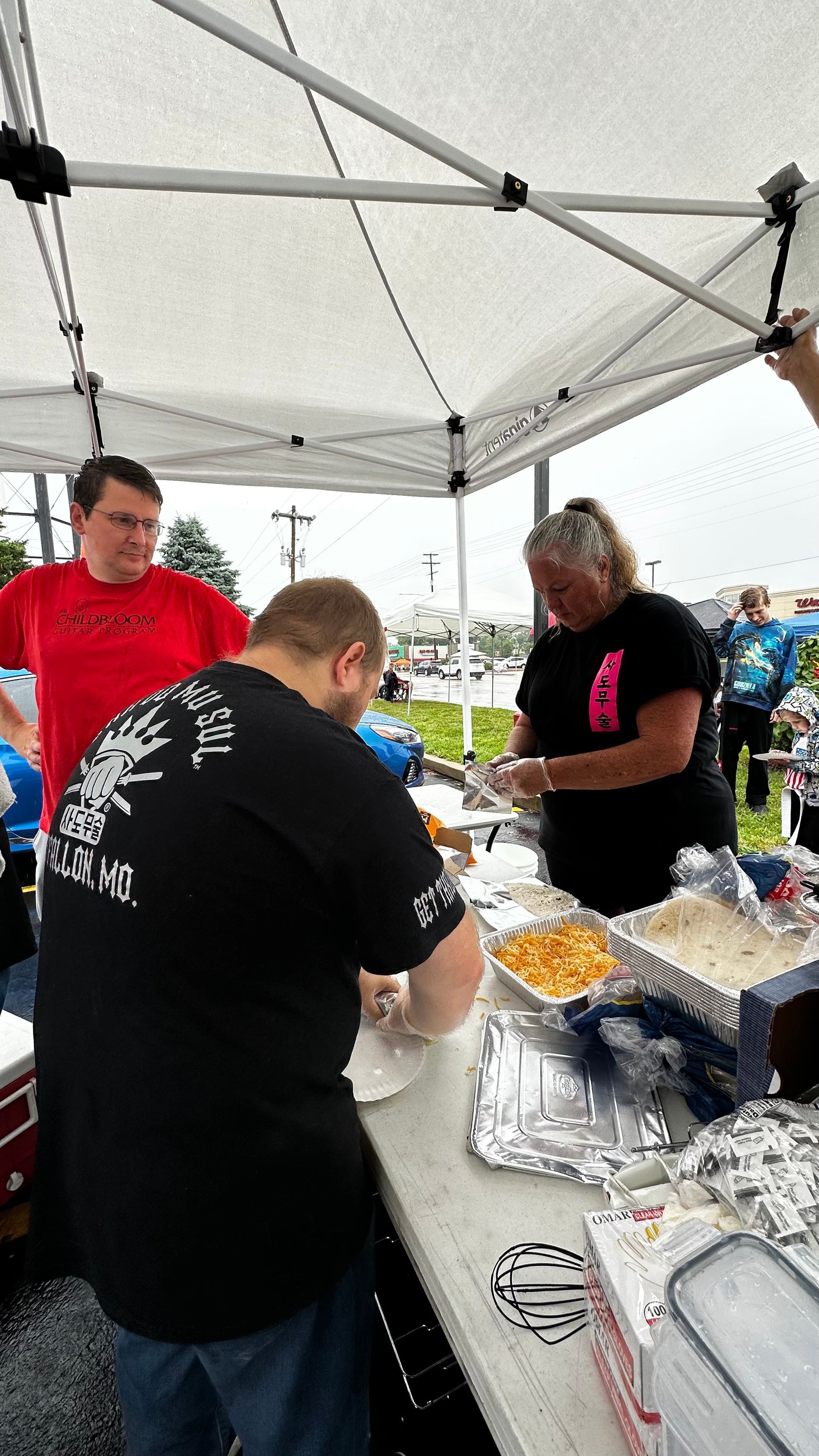 A group of people are standing around a table under a tent.