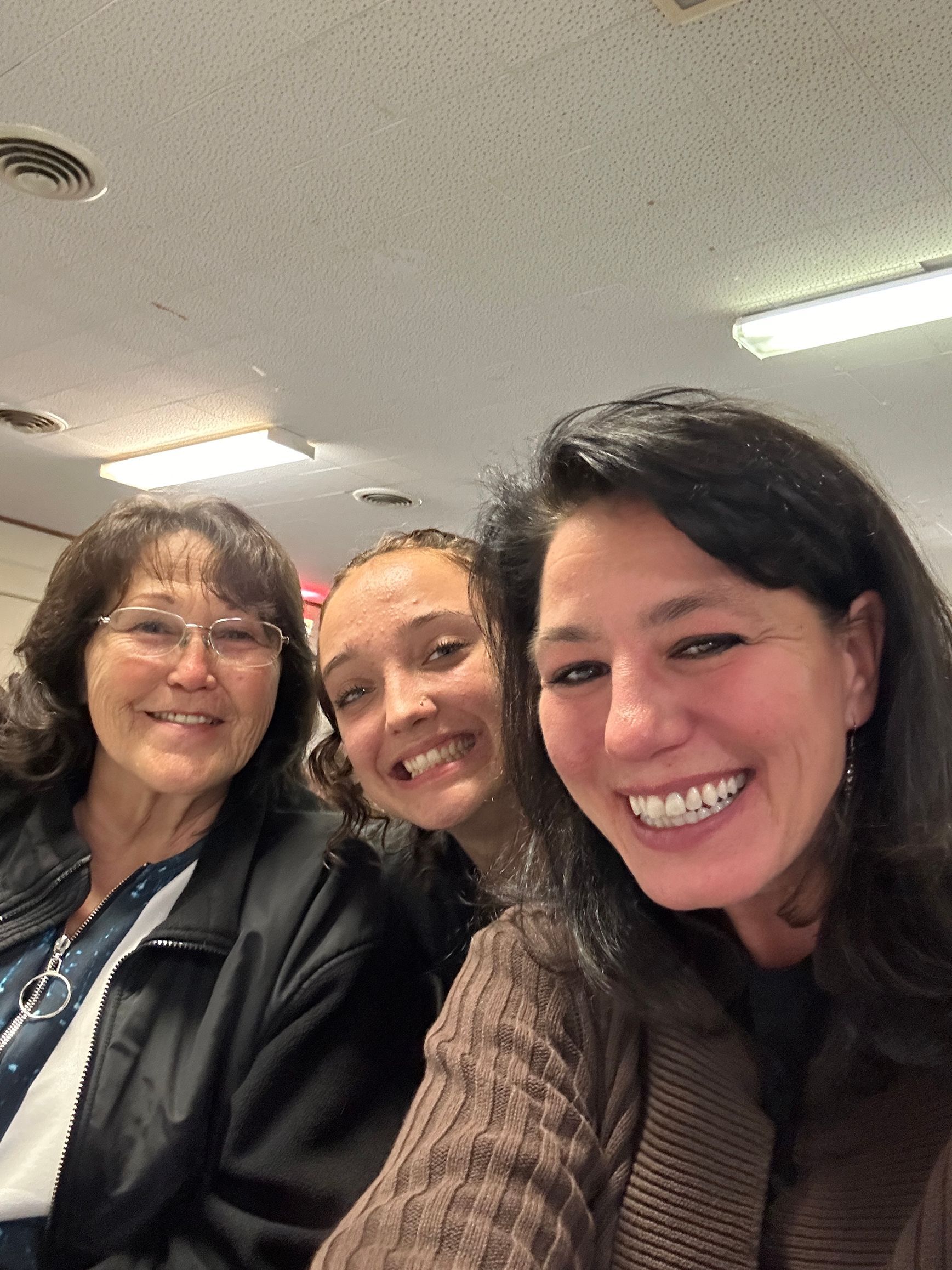 Three women are posing for a picture together and smiling for the camera.