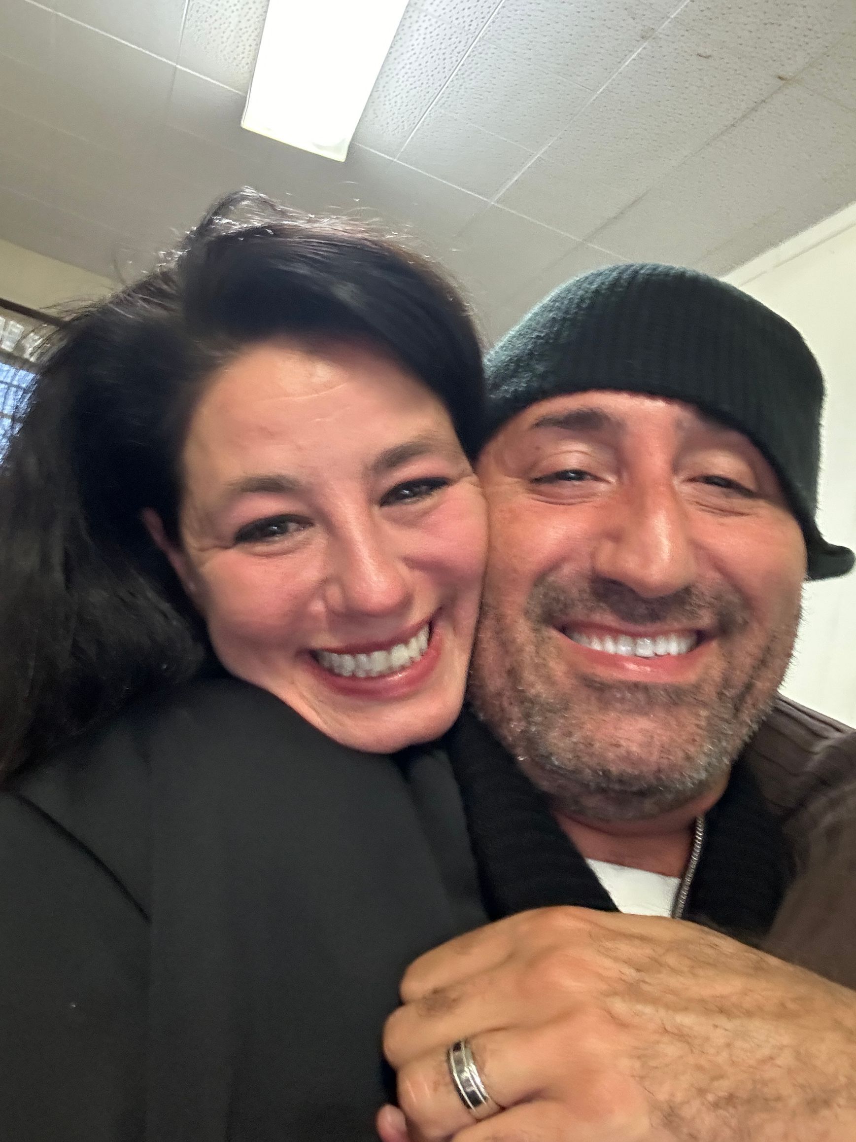 A man and a woman are hugging and smiling for the camera