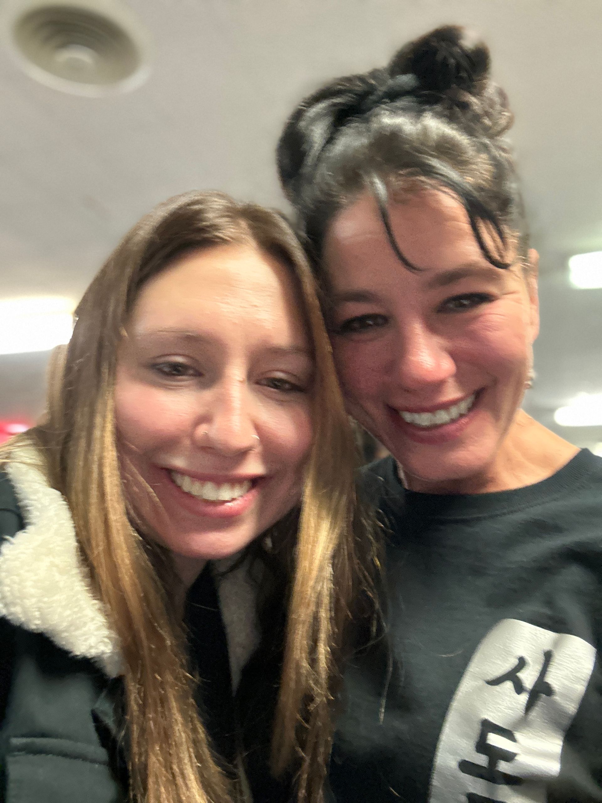 Two women are posing for a picture together and smiling for the camera.