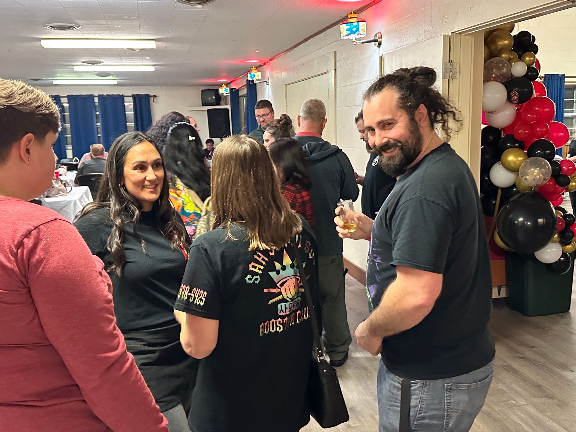 A group of people are standing in a room talking to each other.