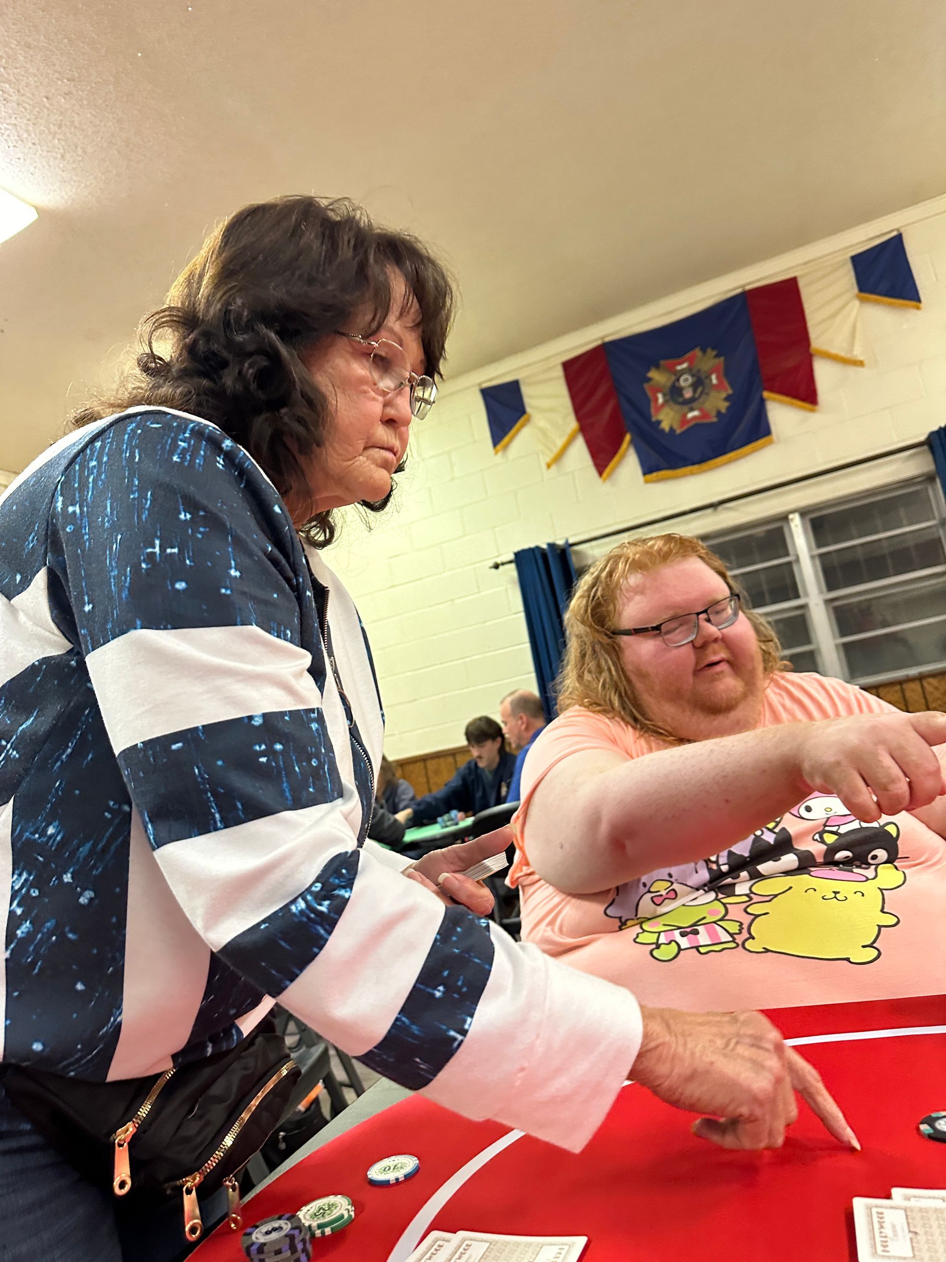 A woman is standing next to a man playing a game of poker.
