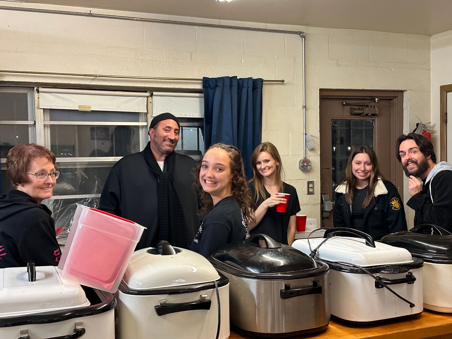 A group of people are standing around a table with pots and pans.