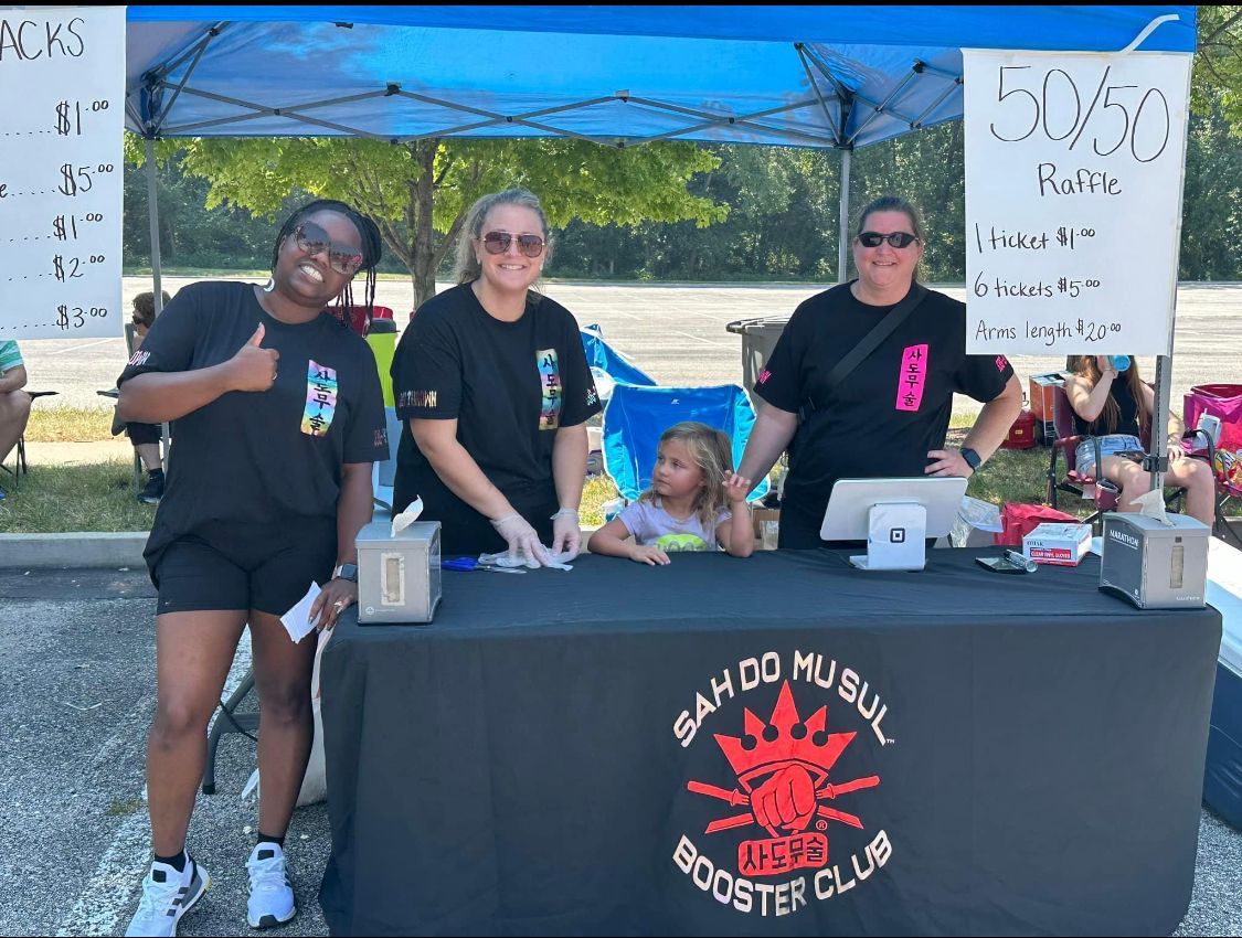 A group of people standing around a table that says booster club