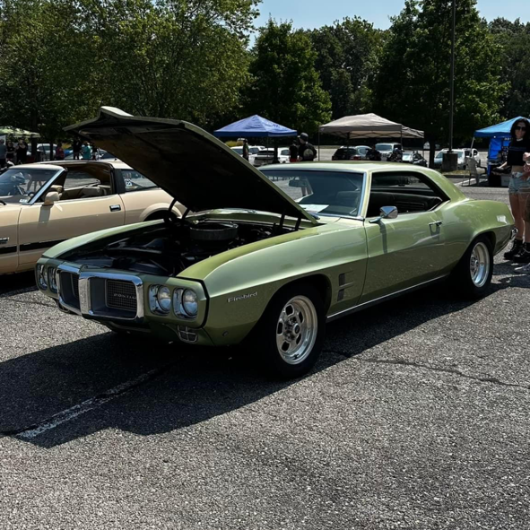 A green car with the hood up is parked in a parking lot