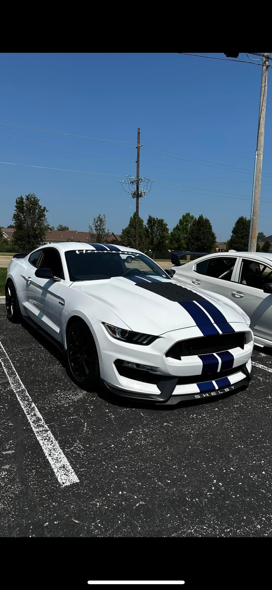 A white ford mustang is parked in a parking lot.